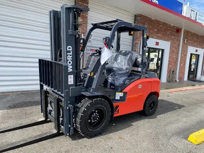 Red forklift parked outside a storefront, with a black mast and red body.