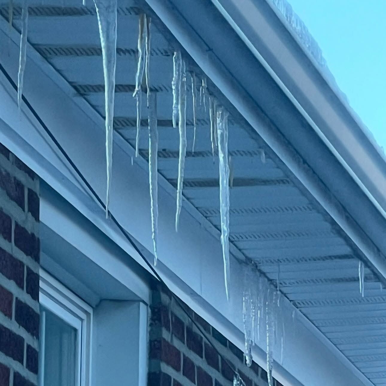 Icicles hanging from a house roof edge in winter