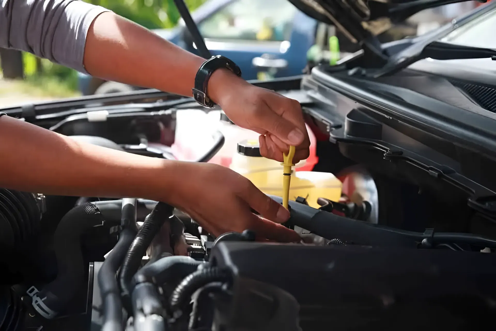 Hands Checking Car's Oil Level With a Dipstick Under the Hood of a Car — Innisfail Pro Motors in Tablelands, QLD