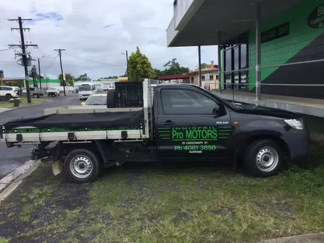 Black pickup truck parked on grass, side view. Reads 