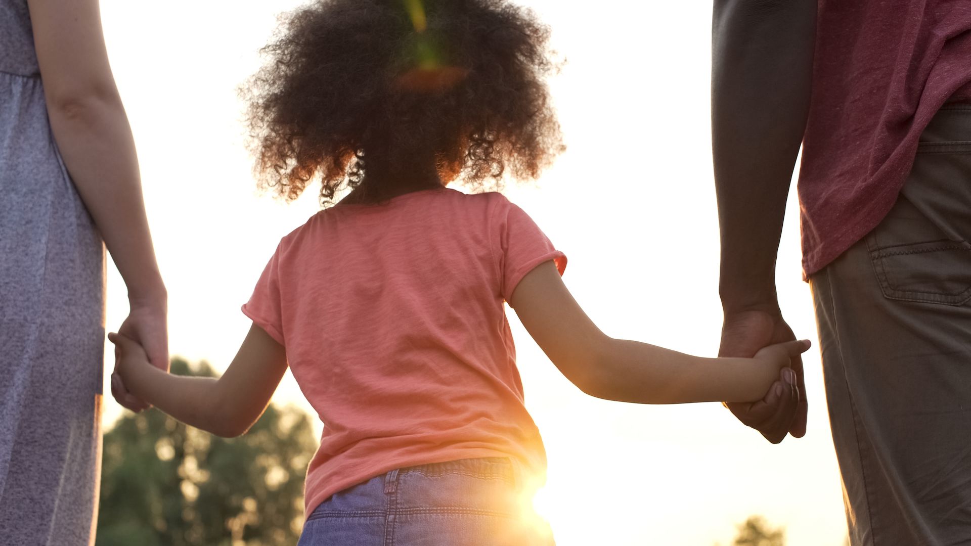 Girl holding her parents' hands, showing the family bonds at stake in a child custody modification