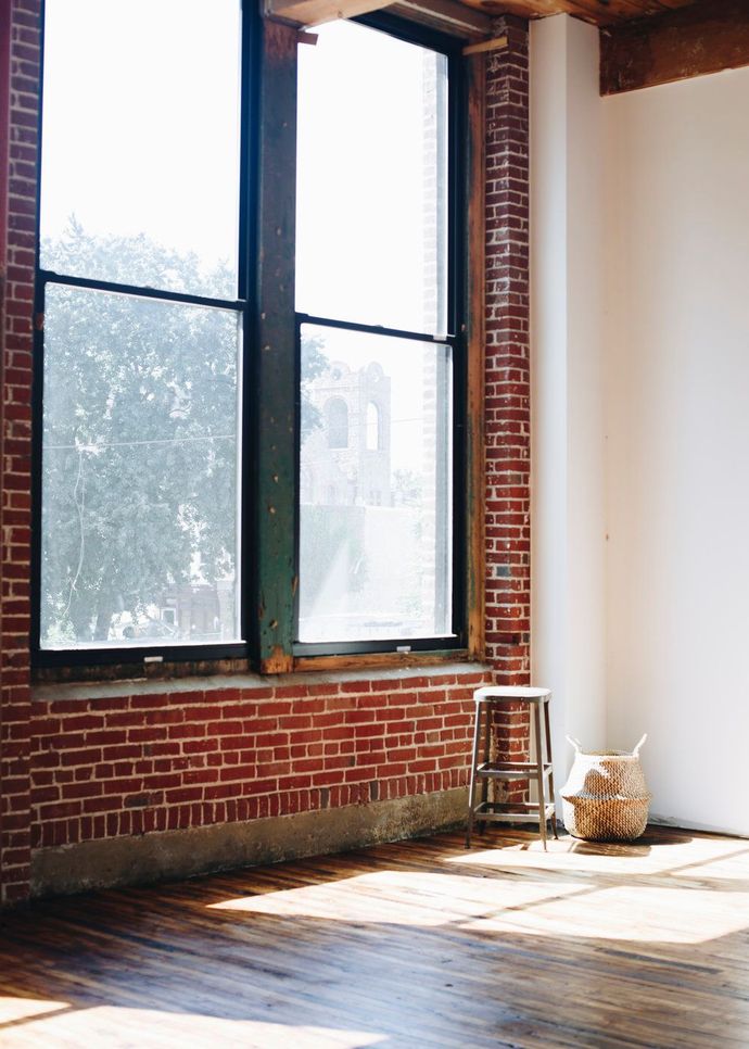 an empty room with a brick wall and two windows .