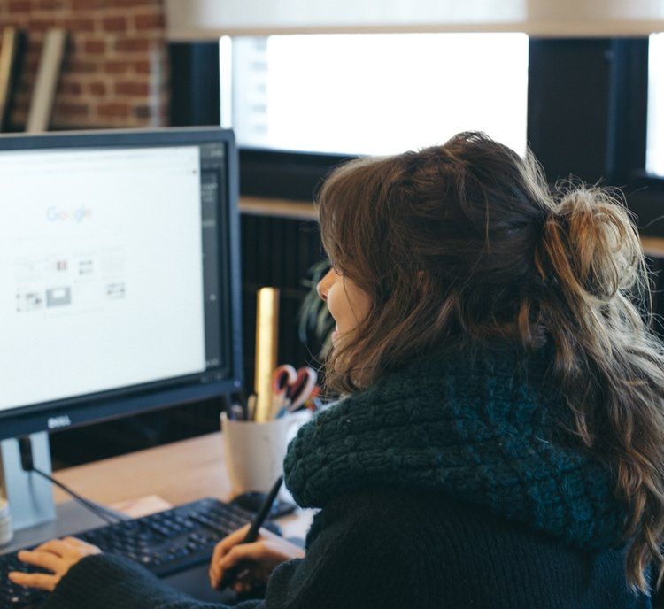 a woman is sitting in front of a computer with a pen in her hand .