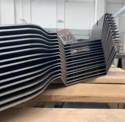 Vassoi neri impilati su un tavolo di legno in un'officina o in un magazzino.