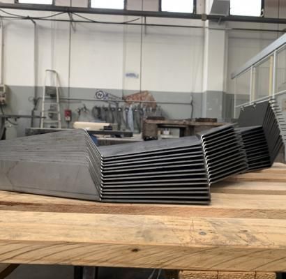 Pile di vassoi di metallo nero su un banco da lavoro in legno in un'officina industriale.