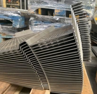 In un magazzino, staffe o binari in metallo argentato impilati e disposti ordinatamente su un pallet.