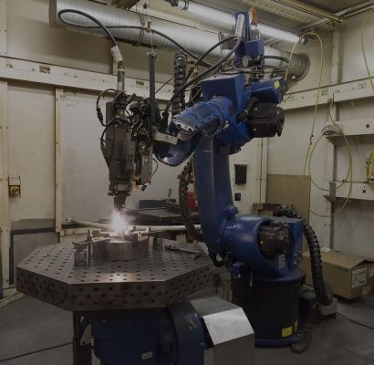 Braccio robotico industriale blu per la saldatura di parti metalliche in un'officina