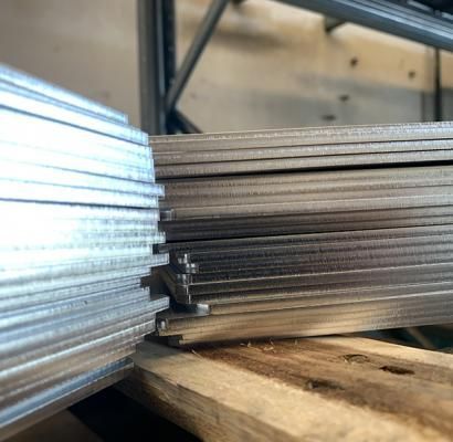 Pile di lamiere metalliche su un pallet di legno in un magazzino.
