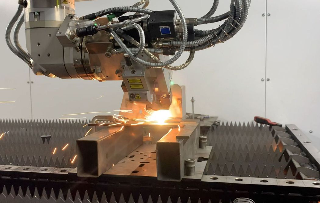 Un robot industriale salda parti metalliche, con scintille brillanti in un ambiente di fabbrica.