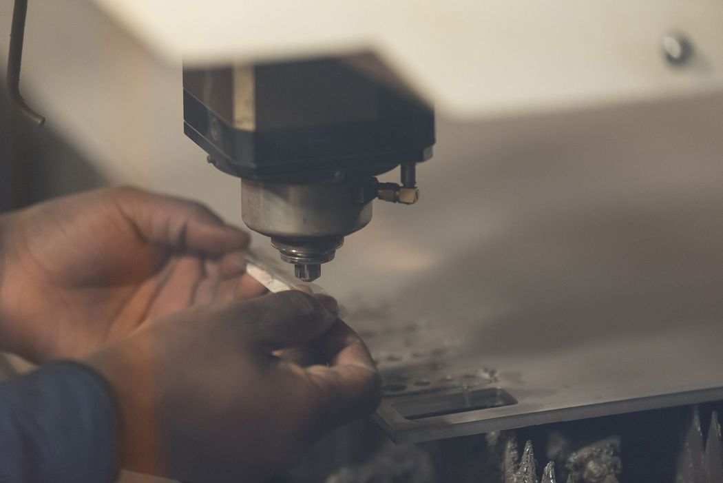 Mani che regolano un piccolo componente sotto una macchina utensile in un'officina