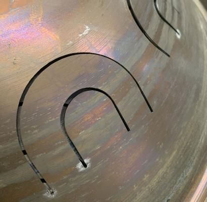 Superficie metallica astratta con riflessi iridescenti e motivi a linee curve nere