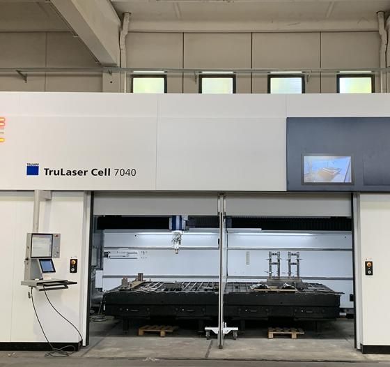 Una grande macchina da taglio laser industriale di colore bianco, all'interno di una fabbrica, reca l'etichetta TruLaser Cell 7040.
