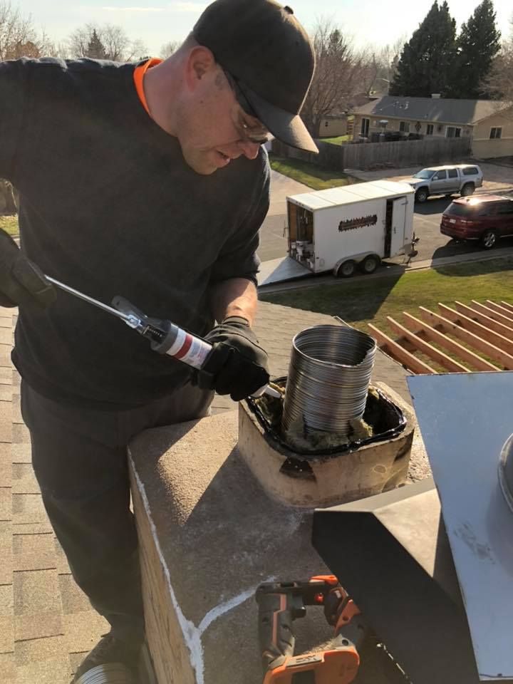 A man is working on a chimney on top of a roof.