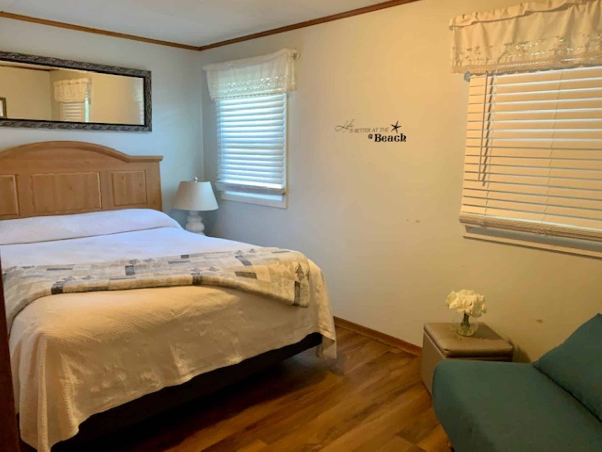 A bedroom with a bed , couch , lamp and mirror.