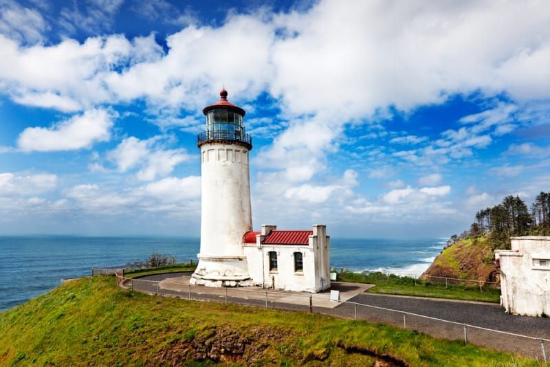 A lighthouse on top of a hill overlooking the ocean.