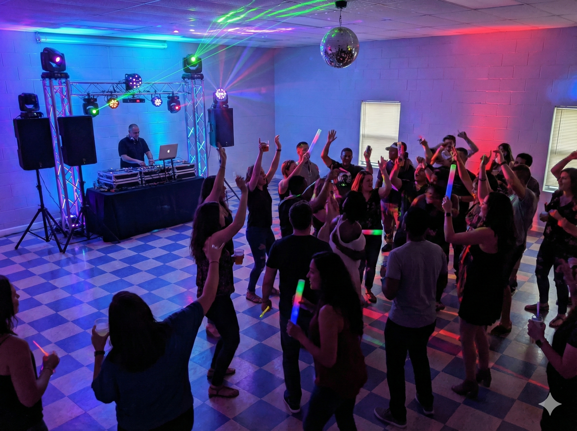 Party with DJ in a room with a disco ball, people dancing and holding glow sticks, colorful lighting.
