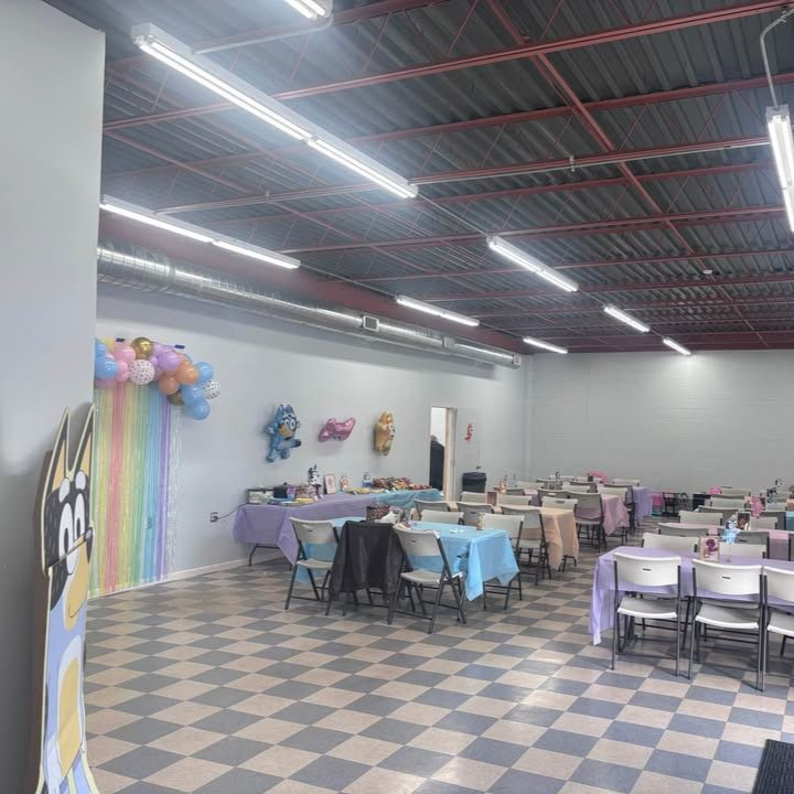 Party venue with tables set, decorated with balloons and pastel colors.