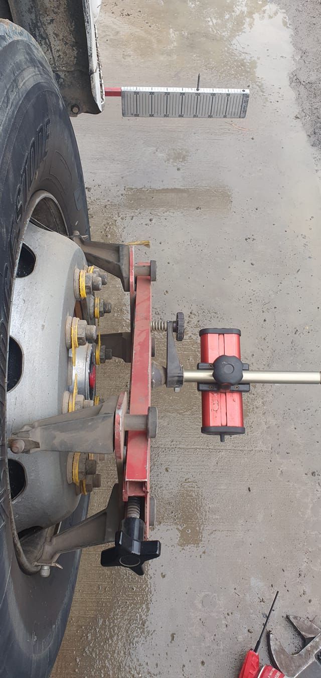 Red wheel alignment tool attached to a car tire on a concrete floor