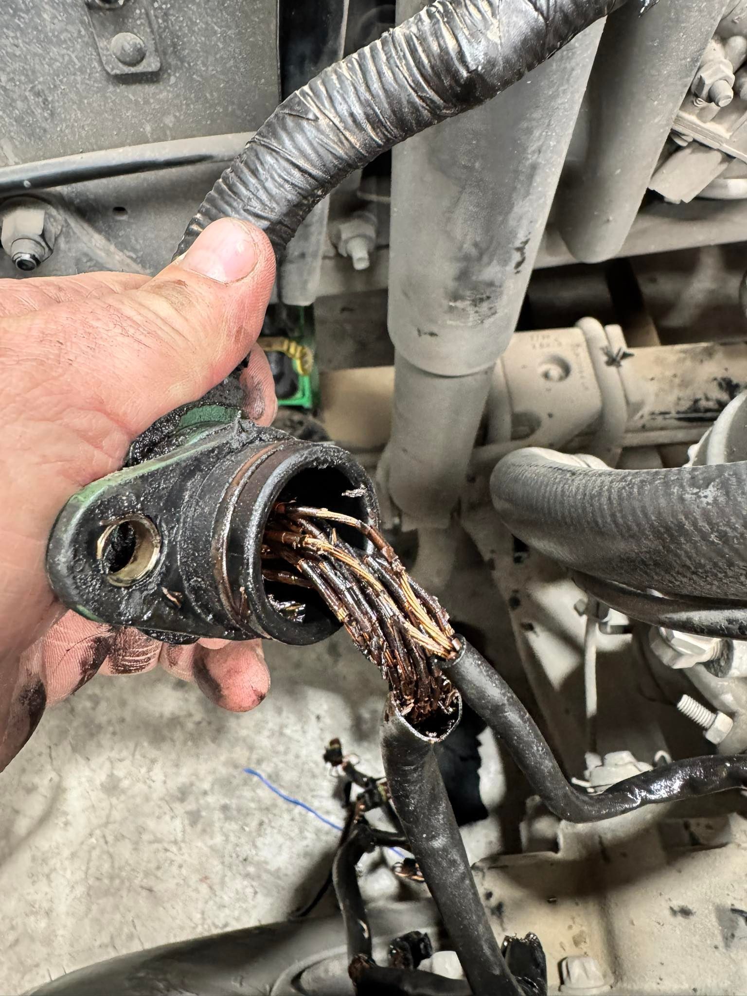 Melted electrical connector with exposed wires in an engine bay, held by a hand — B & W Commercials In Wauchope, NSW