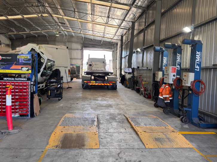 Auto repair garage with a truck on a lift, tools, and work bays inside a metal-roofed shop — B & W Commercials In Wauchope, NSW