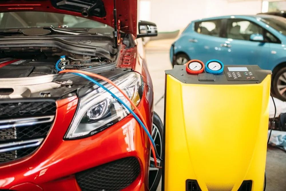 A Yellow Ac Service Machine Connected to the Hood of a Red Car in a Garage — B & W Commercials In Wauchope, NSW