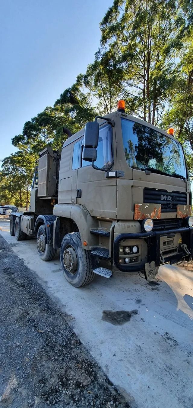 A Military-style Tactical Man Truck Parked on a Gravel Roadside Under Trees — B & W Commercials In Wauchope, NSW