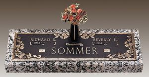 a gravestone with a vase of flowers on top of it .