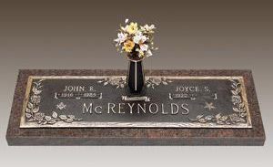 a gravestone with a vase of flowers on top of it .
