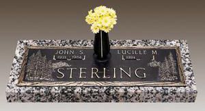 a gravestone with a vase of flowers on top of it .