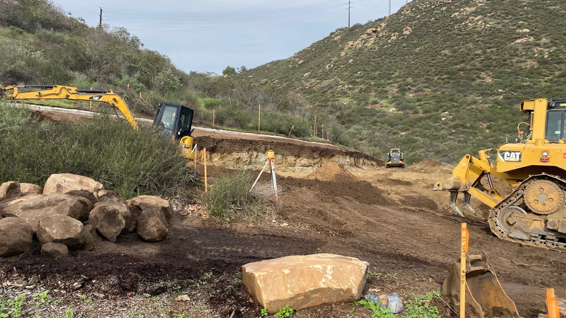 Construction site: Excavators and a bulldozer clear a hillside, earthmoving.