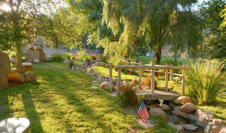 there is a small bridge over a stream in the middle of the garden .