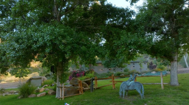a statue of a horse is sitting in the grass in a park .