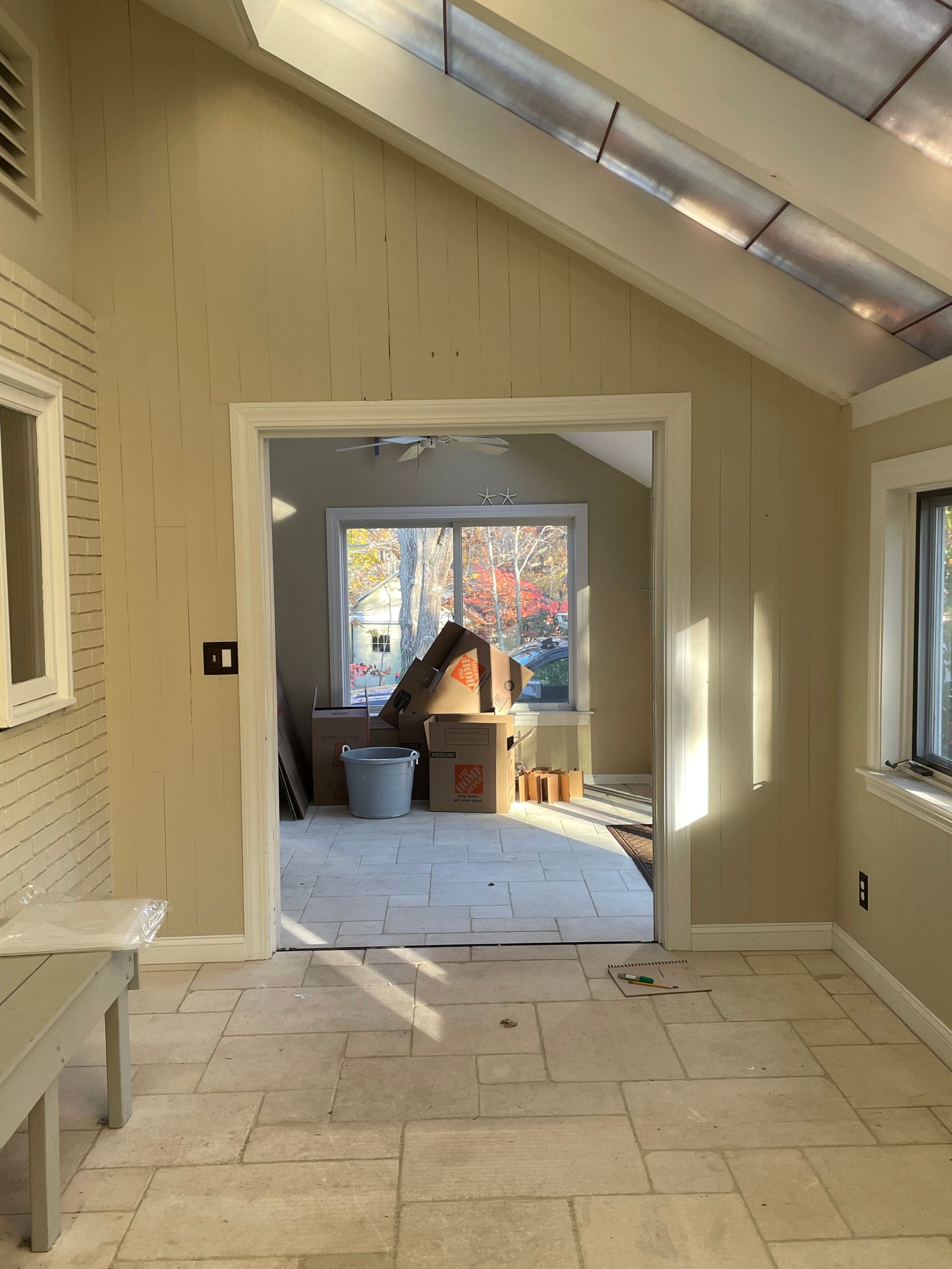 Interior view: Sunroom with tile floor, doorway to room with window, boxes inside.