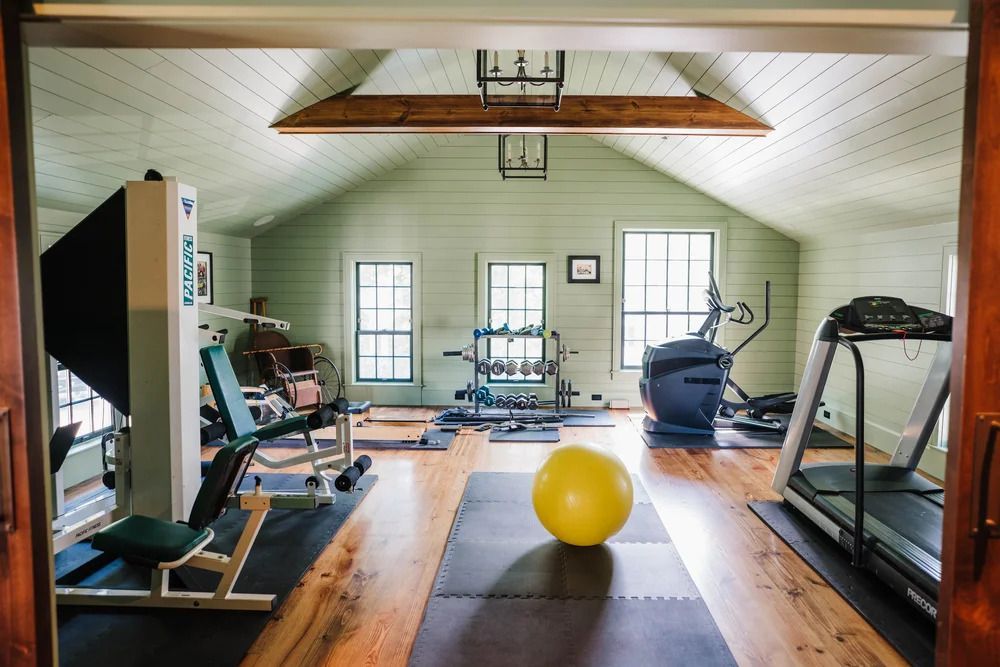Home gym with various equipment, including treadmill, weight machines, and exercise ball.