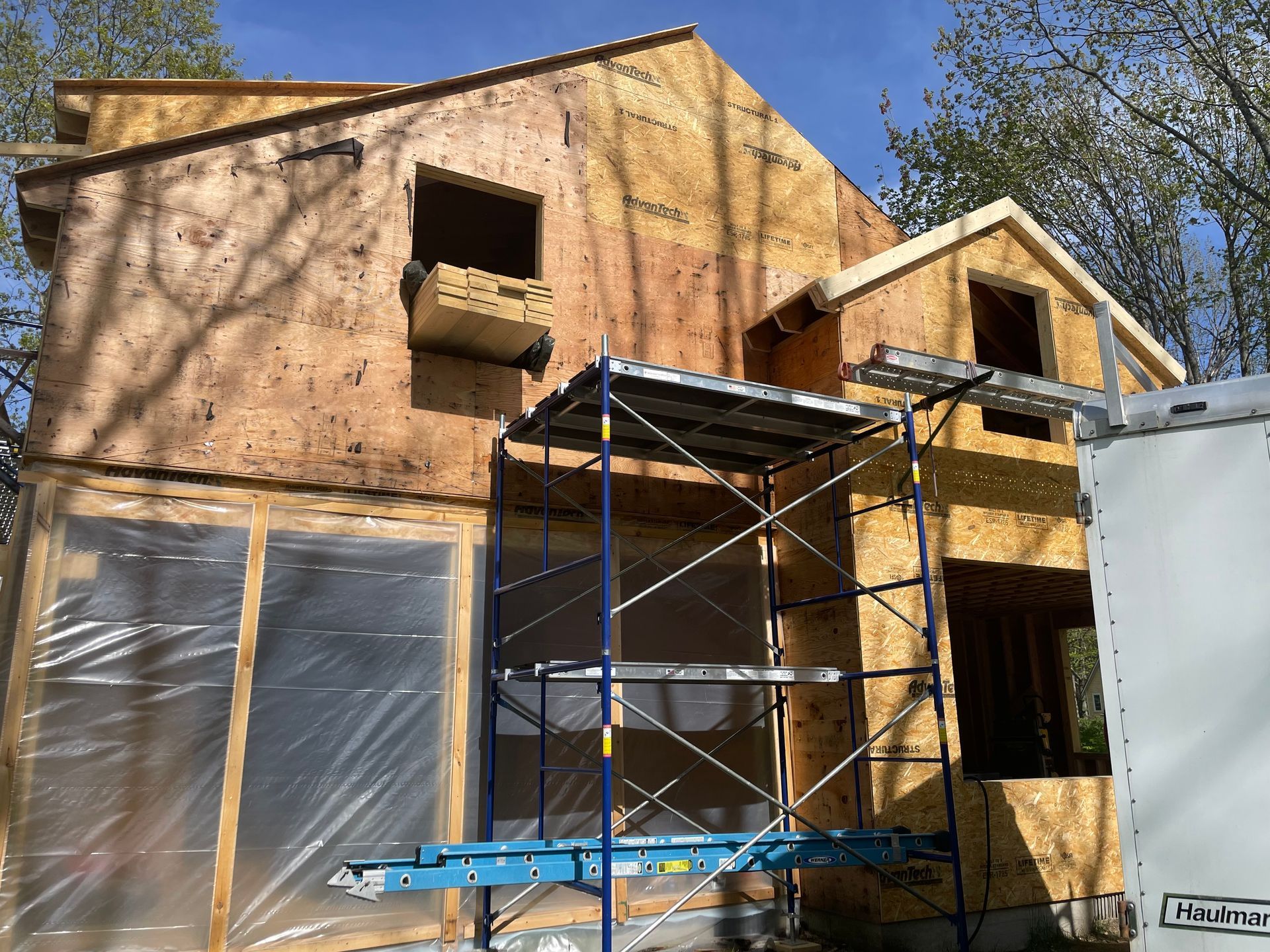 House under construction, wood frame with scaffolding. Windows and siding being added.