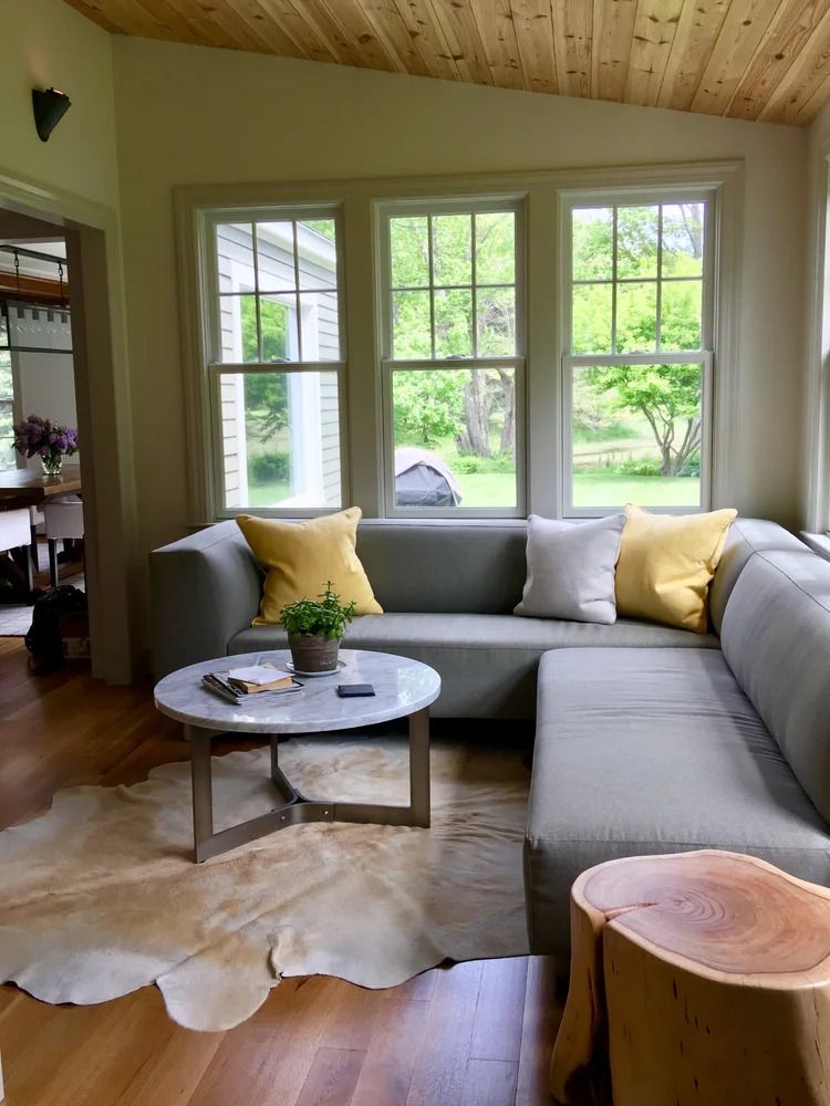 Cozy living room with a gray sectional sofa, yellow pillows, a round coffee table, and a cowhide rug.