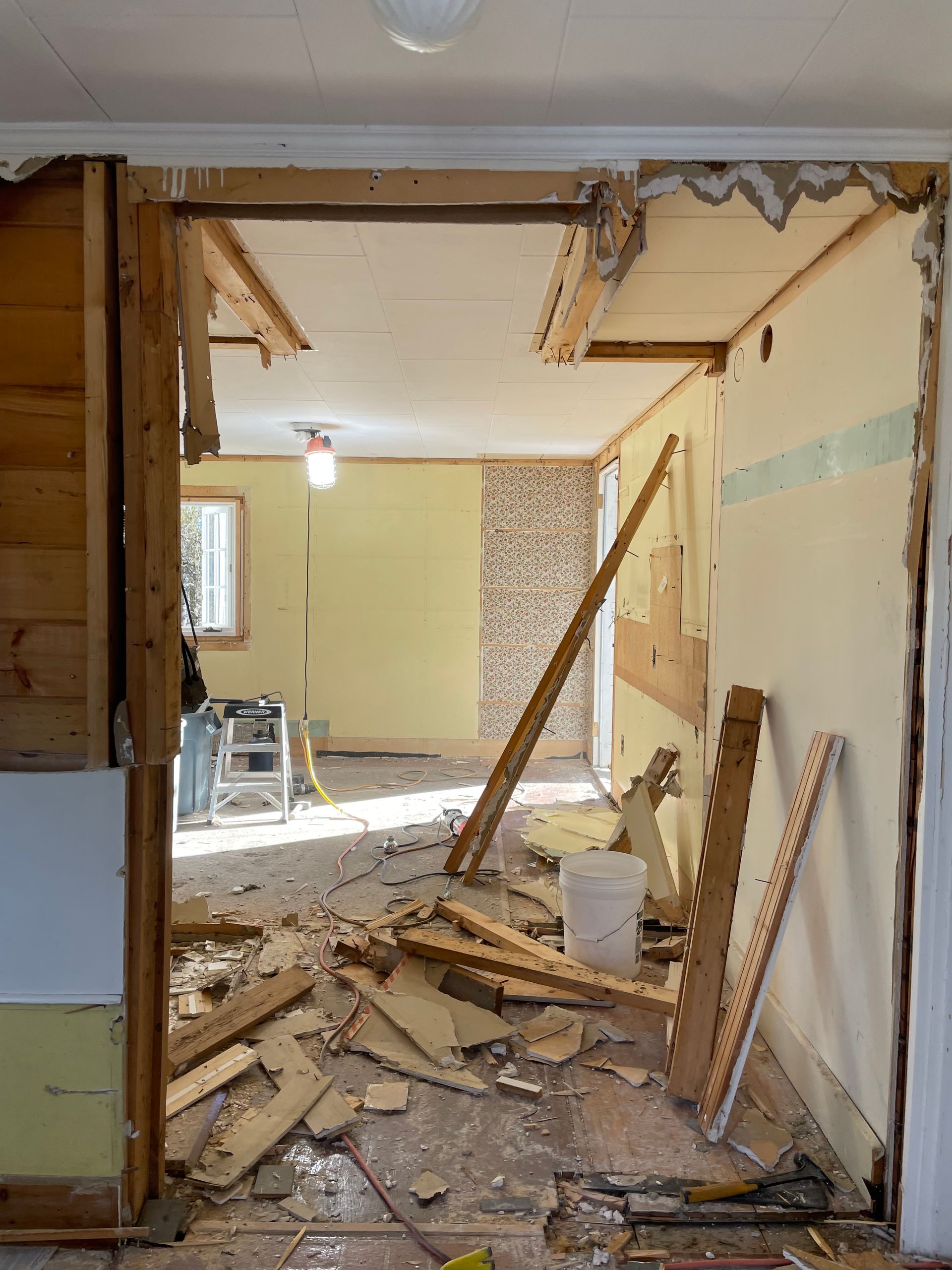 Interior doorway under renovation, debris on floor, yellow walls.