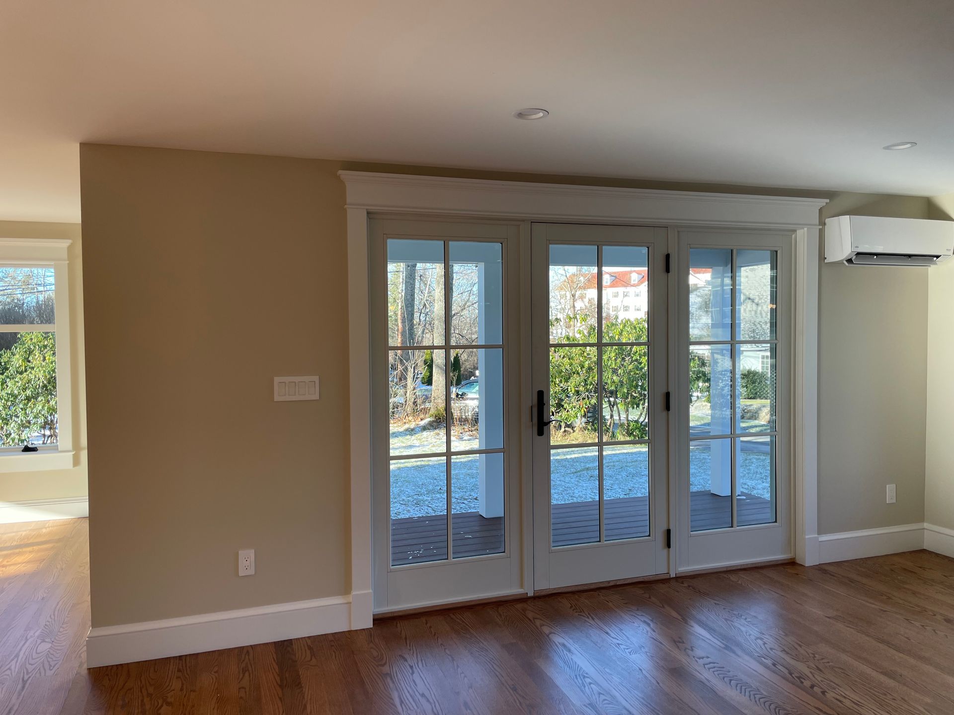 Interior view of room with wood floor, three-panel glass doors, and cream-colored walls.