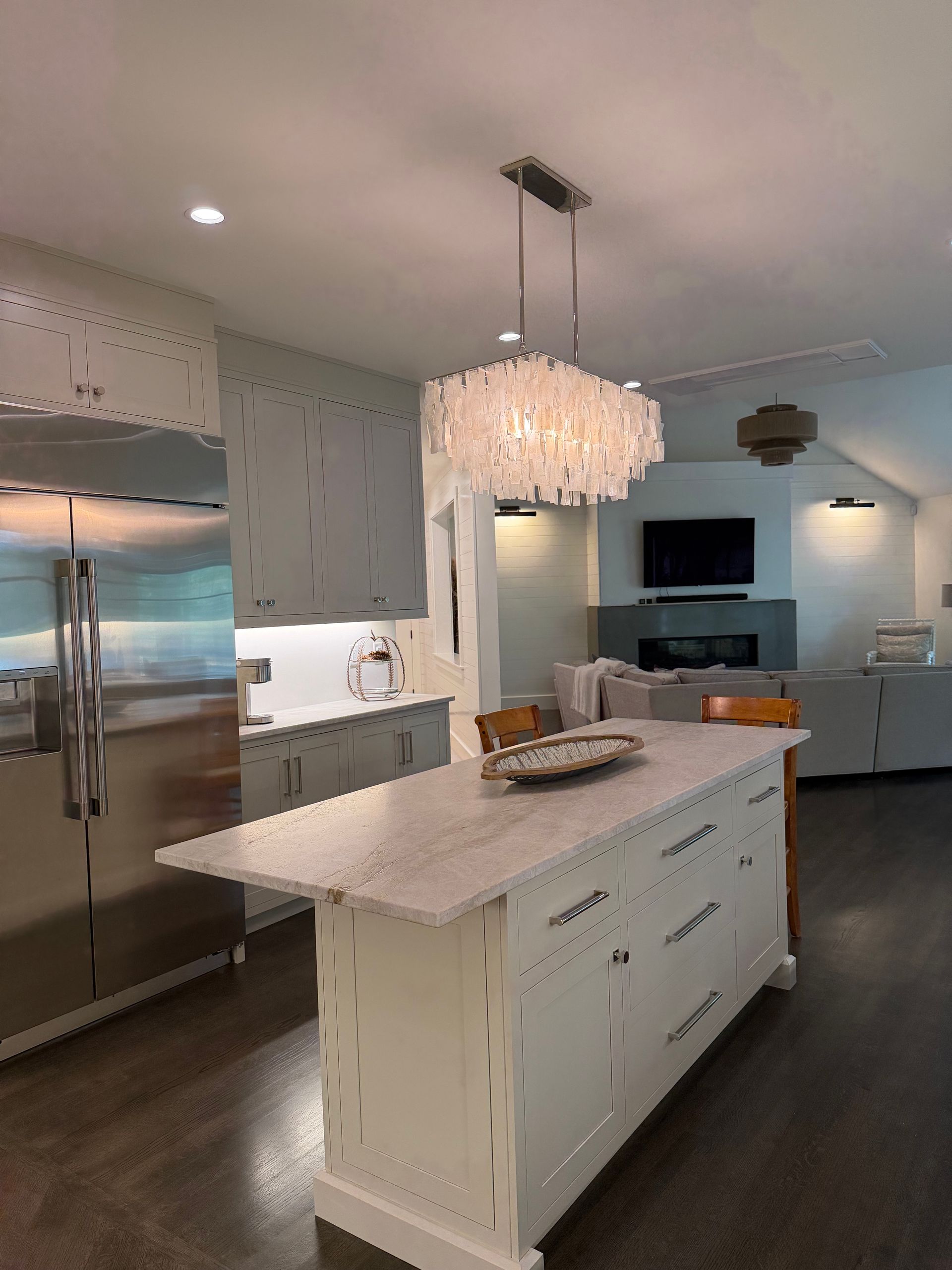 Modern kitchen with white cabinets, stainless steel refrigerator, and central island.