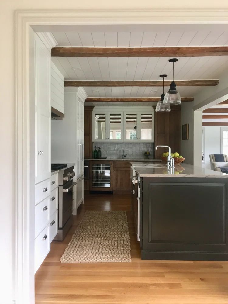 Kitchen with wooden floors, white and brown cabinets, and a gray island.