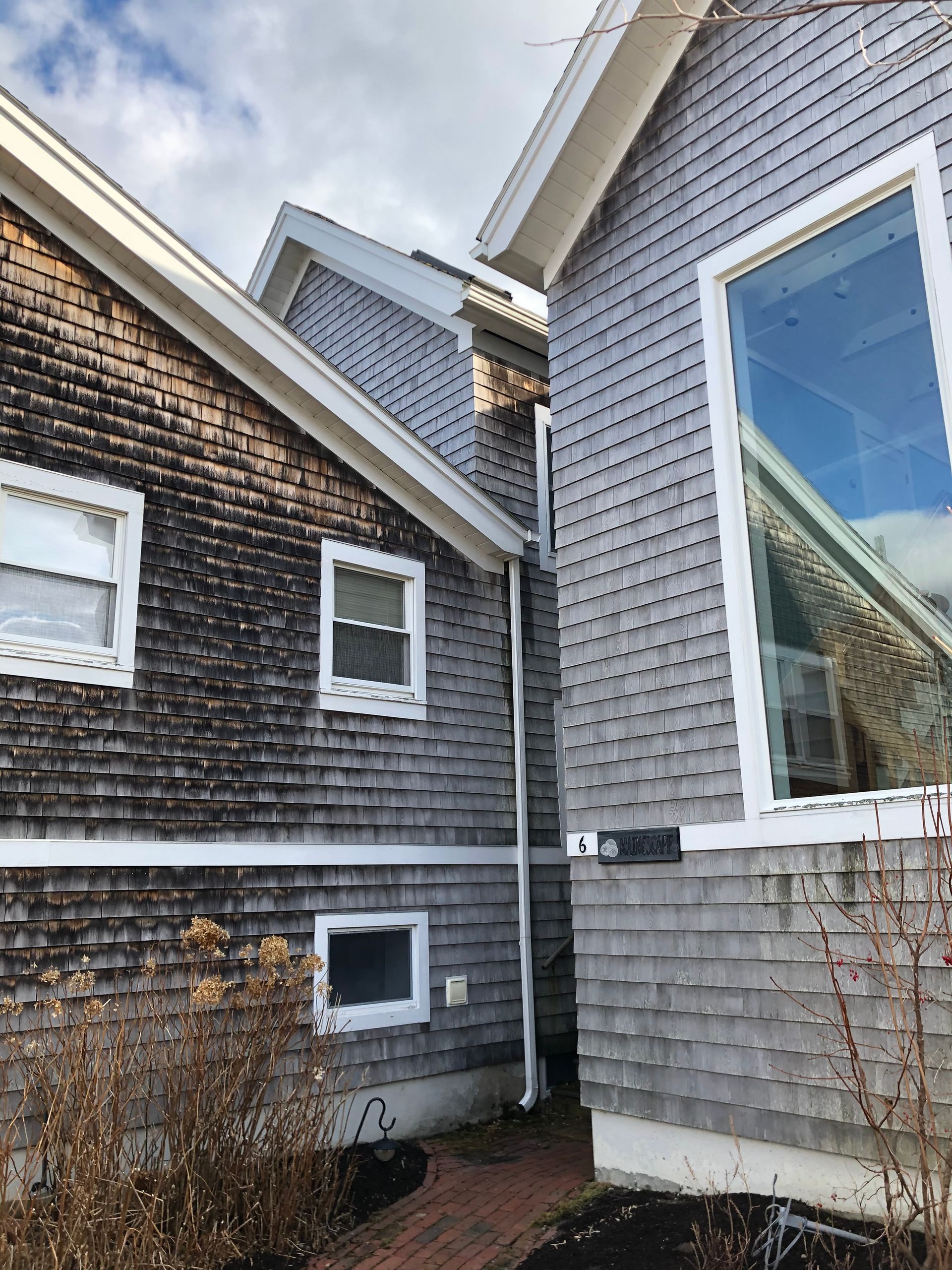 Buildings with weathered gray shingles, windows, and white trim, viewed from a low angle.