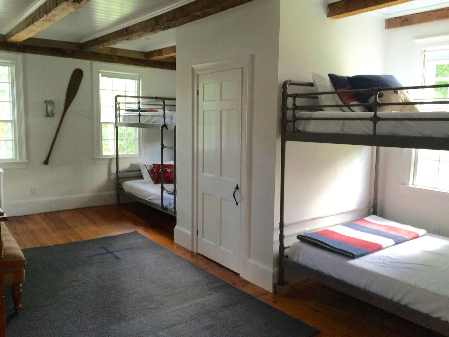 Bunk beds in a bright room with wooden beams and a large oar.