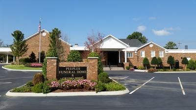 Brick medical building with landscaped entrance and parking lot under a clear blue sky