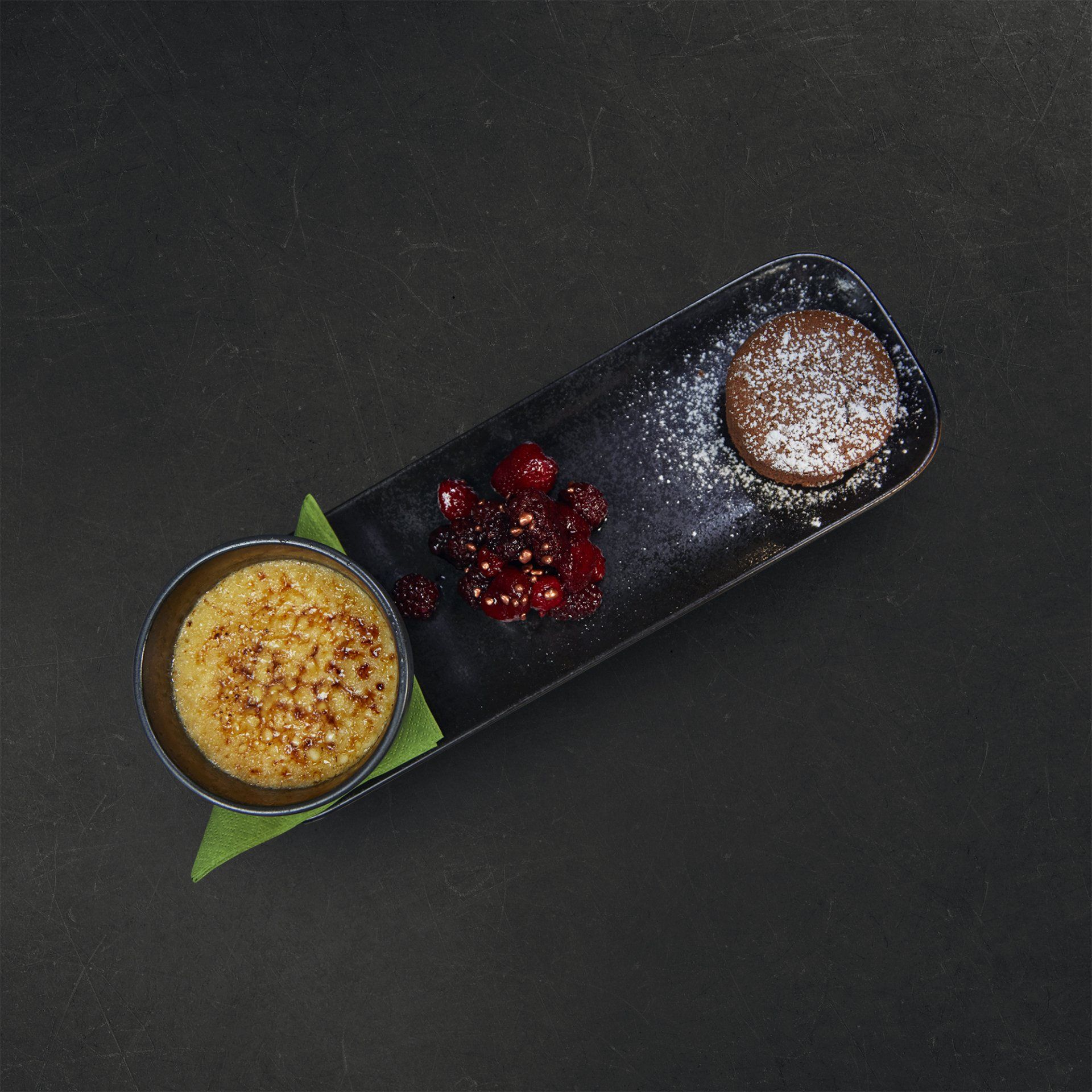 a tray of desserts with powdered sugar and berries on a table .