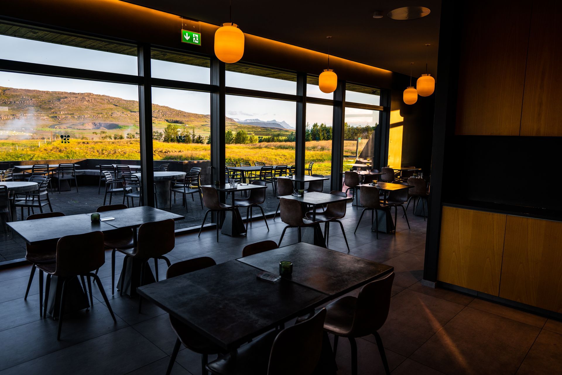 a restaurant with tables and chairs and a large window with a view of a field .