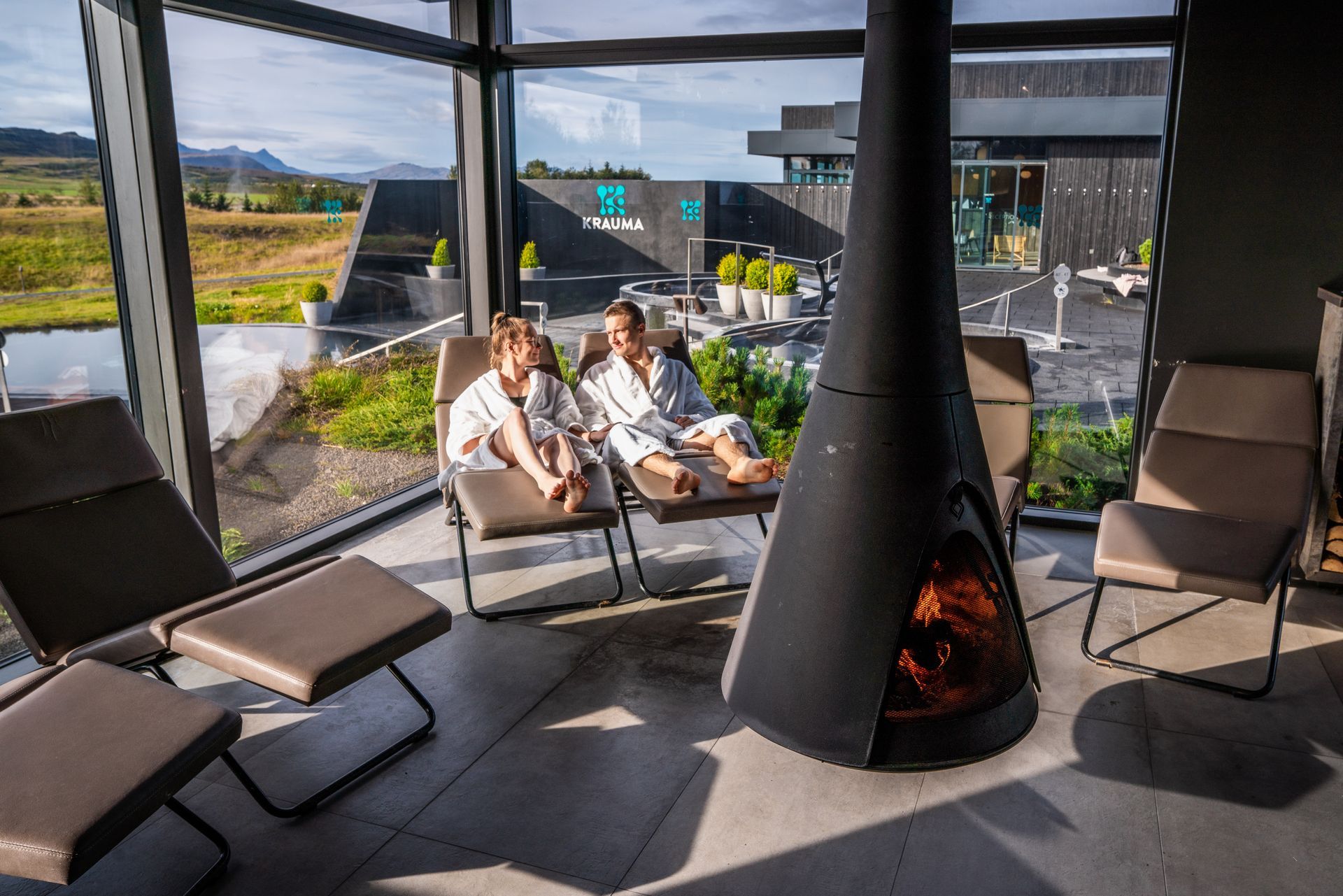 a couple sitting in the relaxation room, enjoying a peaceful drink with relaxing music around the fireplace