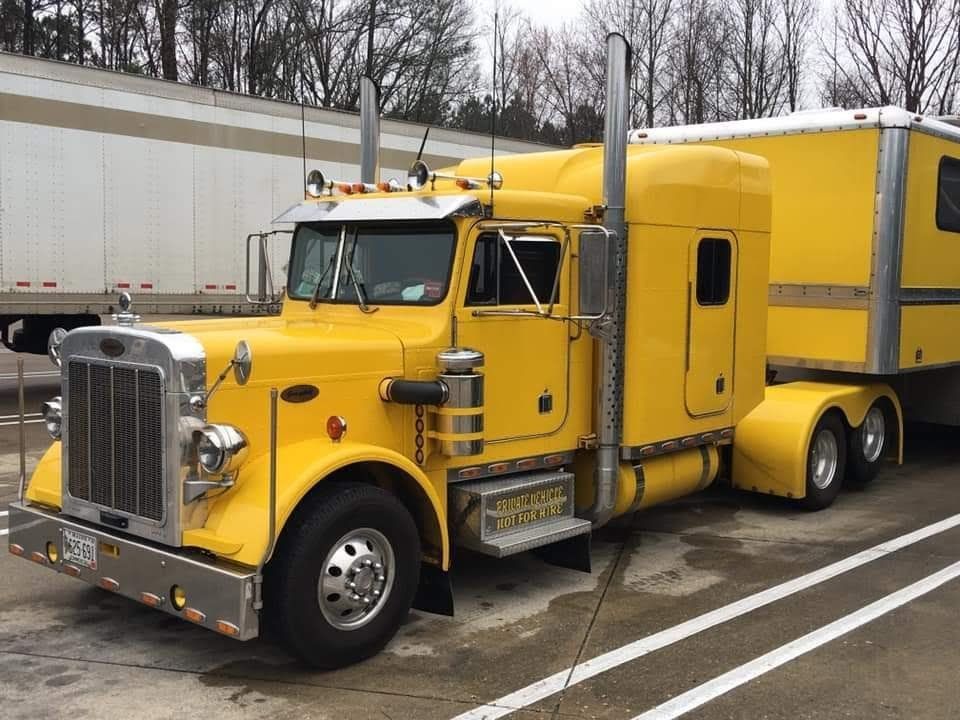 Yellow Peterbilt semi-truck with a matching trailer parked in a lot.