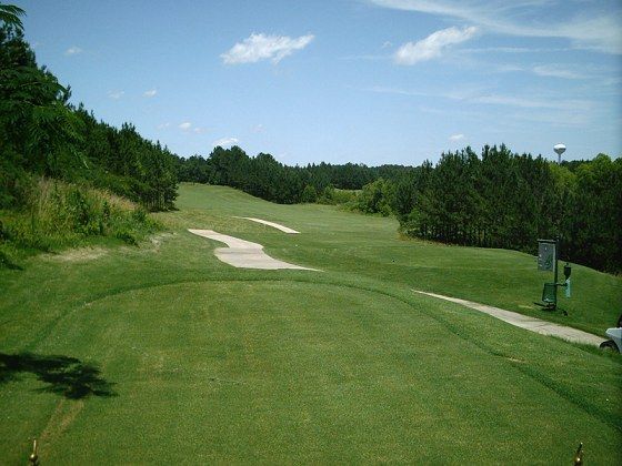 A golf course with a lot of grass and trees on a sunny day