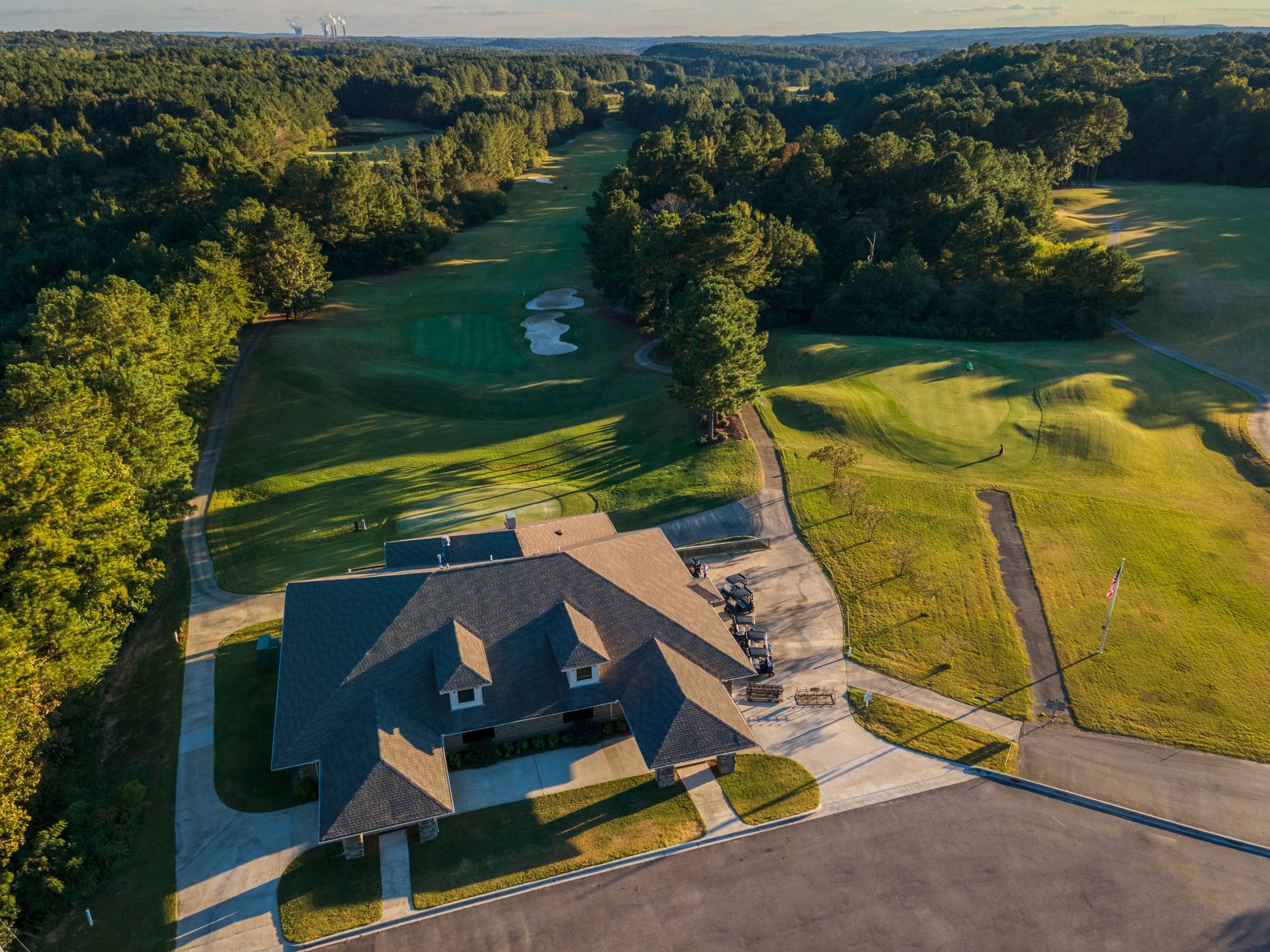 An aerial view of a golf course with a house in the foreground.