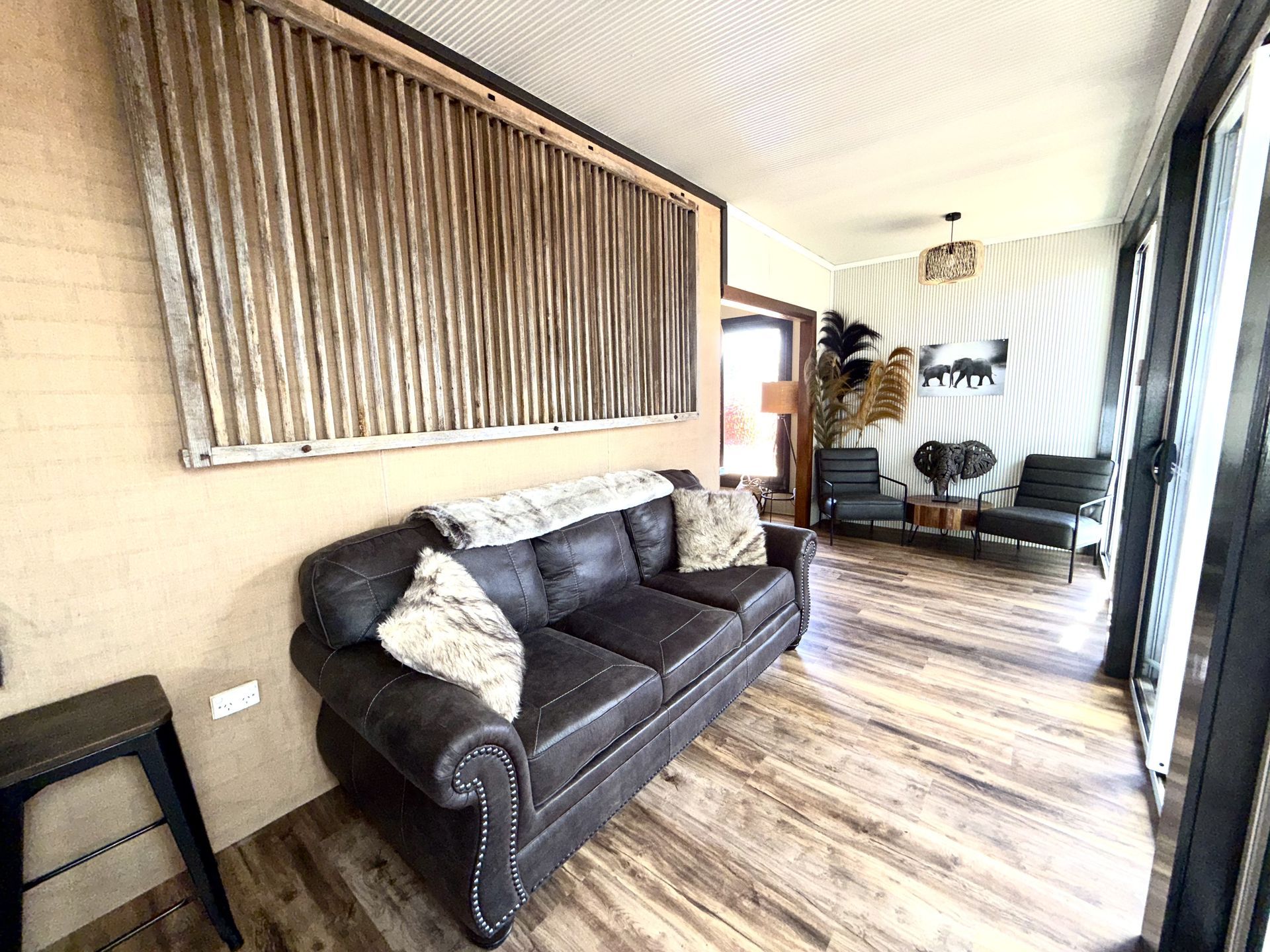 A living room with a couch , chairs , and a large window.